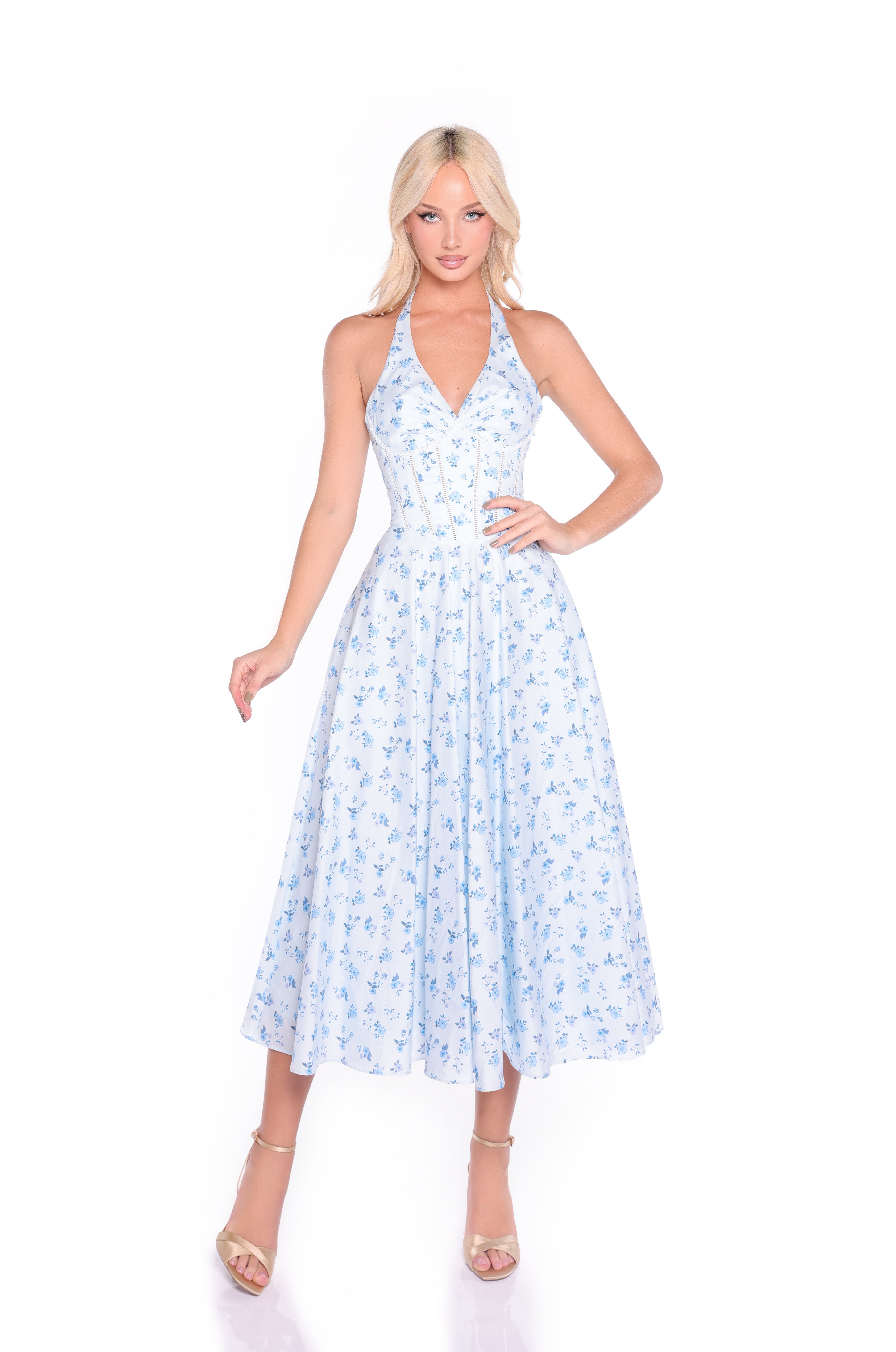 Woman poses in the Eliza Light Blue Floral Halter Summer Midi Dress with a corset bodice and beige heels against a white background.